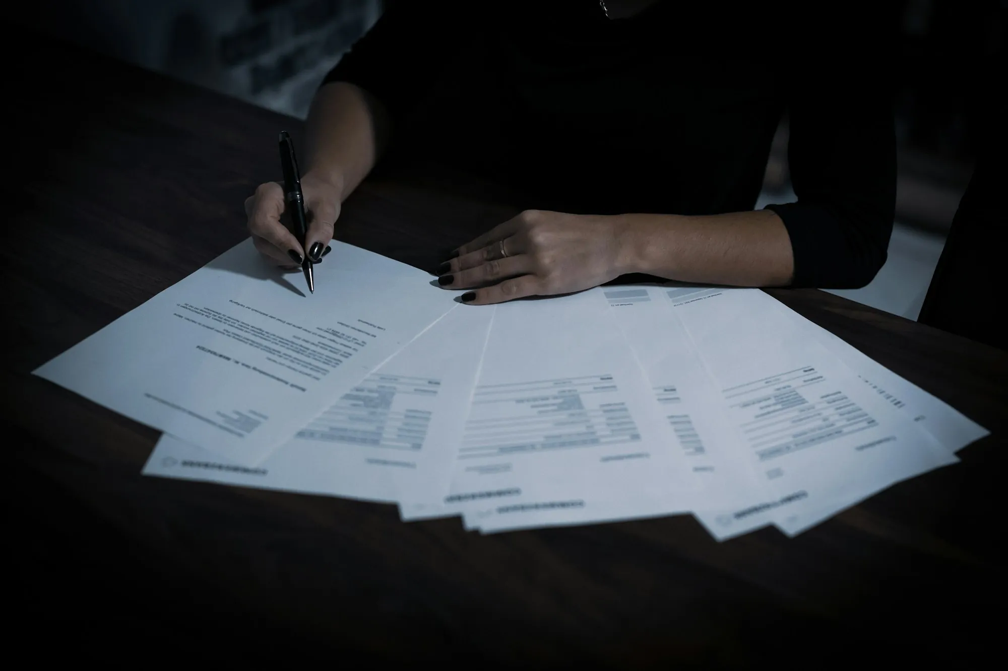 Person reviewing several printed pages on a desk
