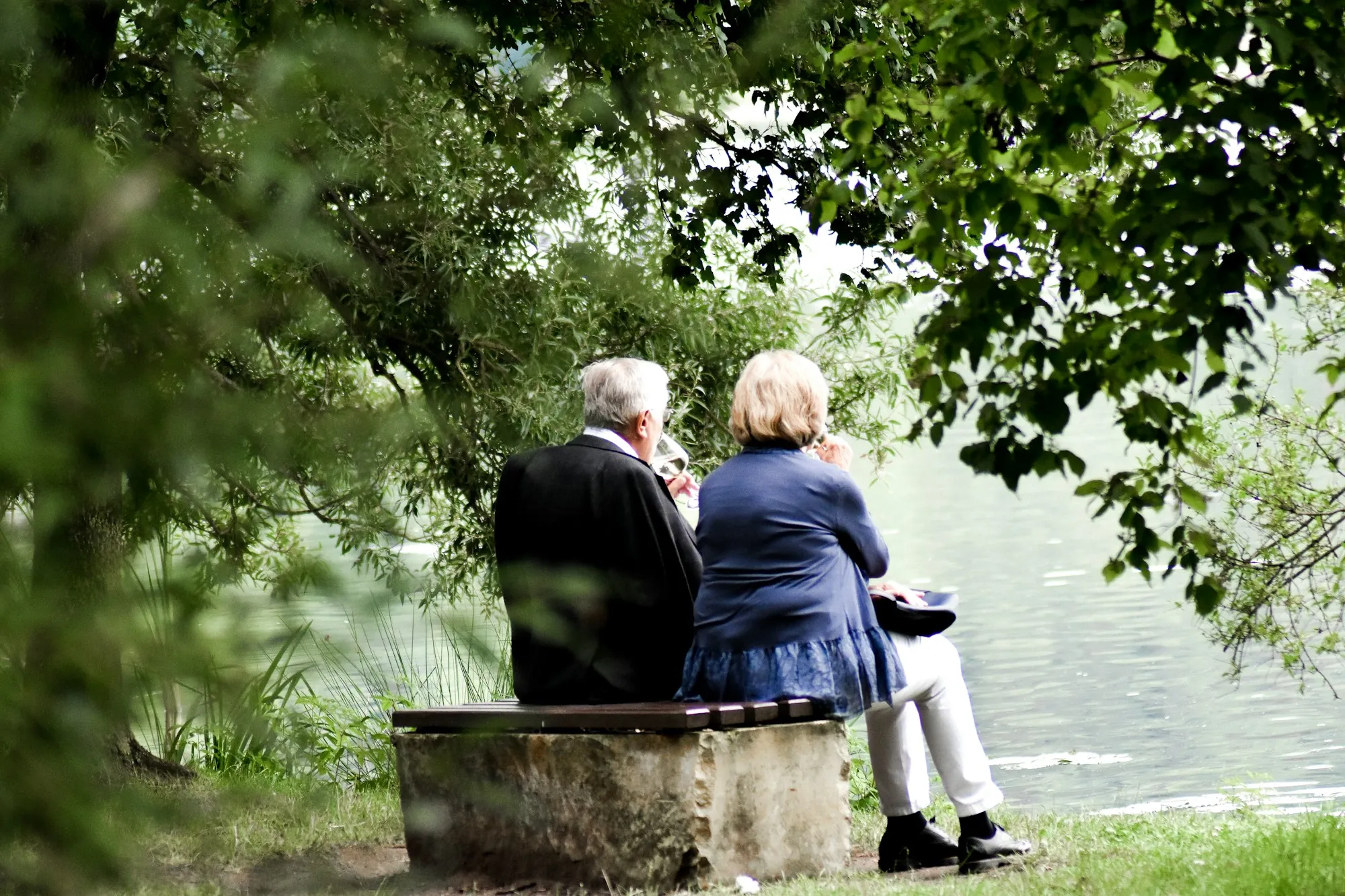 Senior couple sitting on a bench beside a lake, thinking ahead about what final expense insurance covers for a Lake Forest family